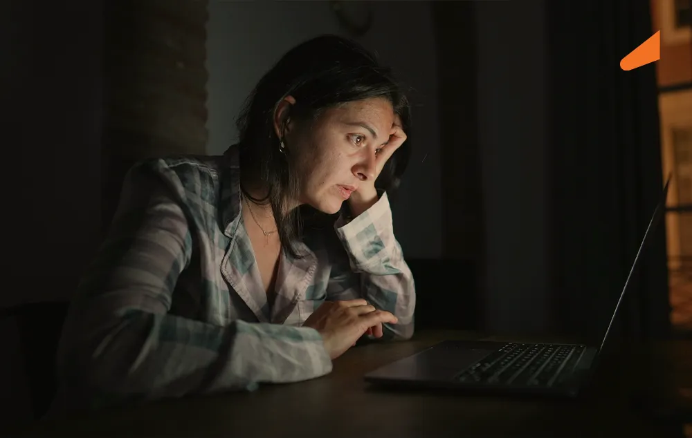 Mulher branca com expressão assustada olhando para um notebook
