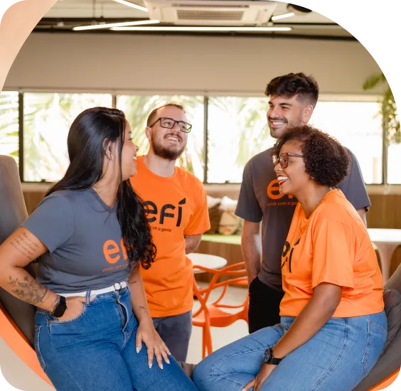 Colaboradores da Efí conversando e sorrindo em uma mesa de reunião